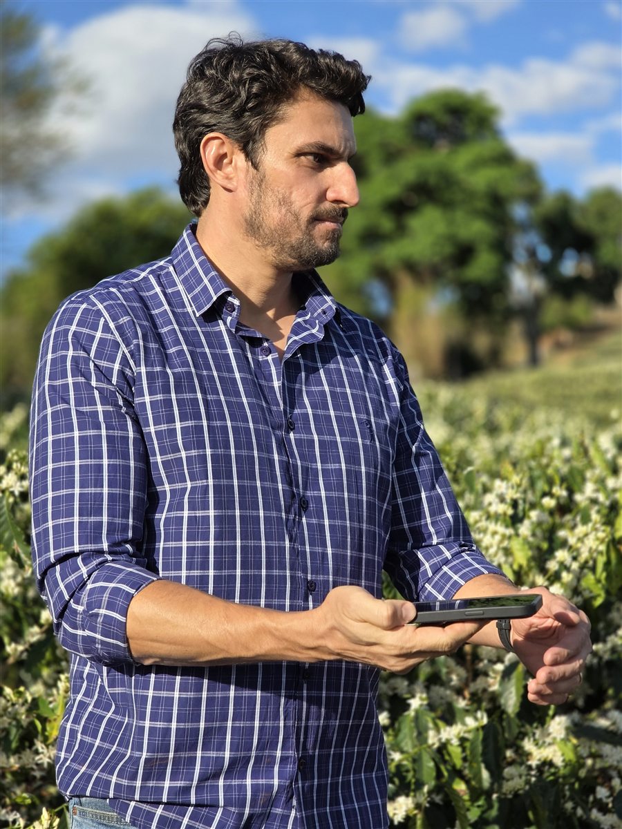 Fábio Kinsch no cafezal, usando o ChatGPT no celular